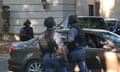 Three members of the Hawks South African police unit standing around a car in helmets and bulletproof vests