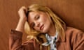 A model crouched down against a wooden background wearing a suede jacket