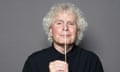 Simon Rattle looking to camera, holding up a baton in front of his face