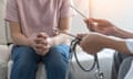 A woman sits on a sofa while talking to a doctor