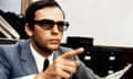 a man in a suit and sunglasses points a finger