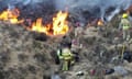 A team of firefighters face a wall of flames in grasslands