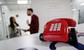 A red telephone on wheels, a mascot for Direct Line Insurance Group Plc, sits on a table as staff members talk in the background in Direct Line's offices