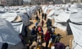 People with yellow water containers stand surrounded by white tents