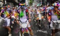 People covered in brightly coloured objects are splashed with water during a street parade