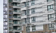 A modern block of flats with its pale-coloured cladding partially removed