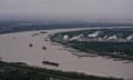 a river bend with barges floating on the waterway.