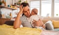 Mother holding her newborn baby looking tired and resting her head on her hand