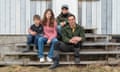 They sit on the steps of a weather-beaten timber-clad home