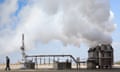 An African worker walks by pipes and chimneys that have steam bellowing out of them