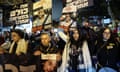 Protest for the release of hostages held in Gaza: it is dark, and people are holding up placards and posters with pictures of the hostages.