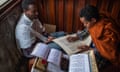 A man writes on parchment while another man talks to him