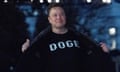 Elon Musk flashes a black T-shirt that says "Doge" outside at night