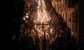 Penitents line a street carrying candles and crucifixes