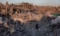 A young woman in a hijab walks among the rubble of Jabalia's destroyed buildings