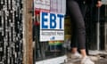 A person stepping out of a door. A sign reading 'EBT Accepted Here' is taped on it.
