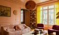 The living room's warming blend of salmon pink and bright yellow, with Alki armchairs and a Japanese chandelier from HK Living.