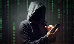 Stock photo of a hooded figure, resembling a crimninal, with a mobile phone