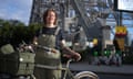 A woman in overalls with bike and bridge in the background