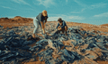 Two people sort through piles of discarded clothes in the Atacama desert